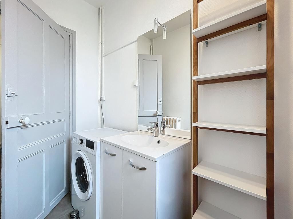 A modern bathroom with a built-in washing machine, a sink, and a mirror.