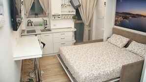 Ein gemütliches Schlafzimmer mit Bett, Schreibtisch und Fenster mit Blick auf die Stadt.