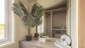 A bathroom vanity with a large mirror, a potted monstera plant, and a decorative tray with a small plant. - Host & Stay | Riverwood, Ashdown Retreat (Pickering)