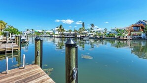 A marina with docked boats, a wooden pier, and buildings with balconies overlooking the water. - Family-Friendly Waterfront Paradise! (Holmes Beach)