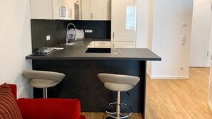 Une cuisine moderne dotée d’un îlot central, de meubles blancs et d’un plan de travail noir.