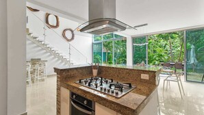 Une cuisine moderne dotée d’un îlot central, d’appareils électroménagers en acier inoxydable et d’un escalier menant à un niveau supérieur.