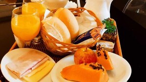 Un plateau de petit-déjeuner avec du pain, du fromage, du jambon, de la papaye et du jus d’orange.