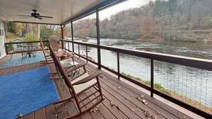 Eine überdachte Terrasse mit Blick auf einen Fluss und Herbstlaub.