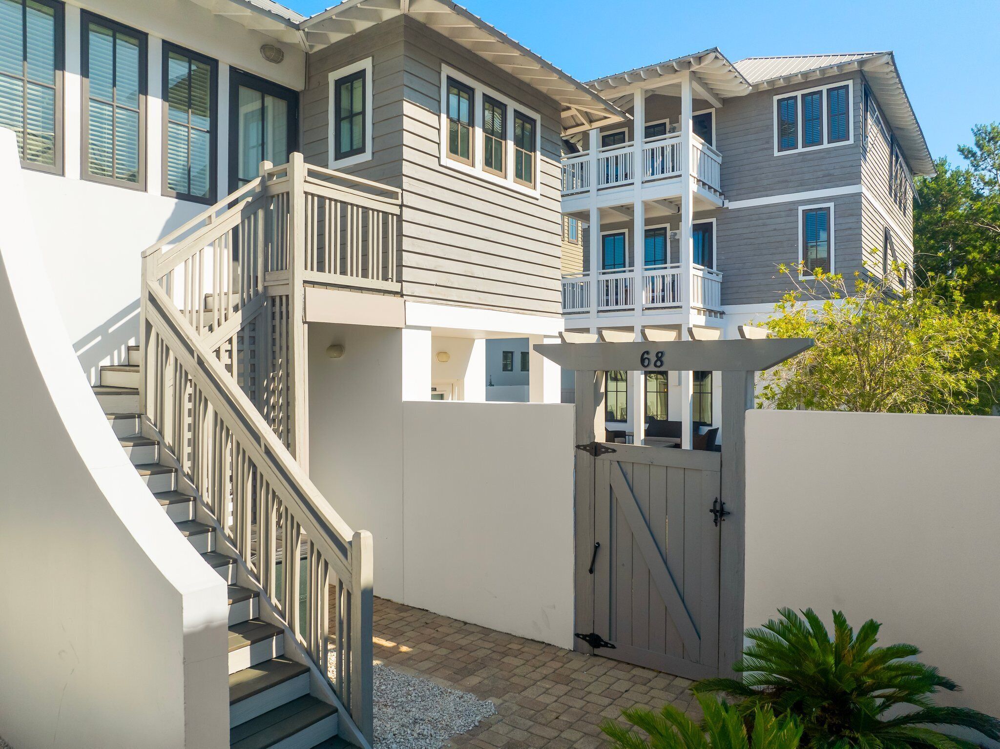 A multi-story house with a gated entrance, a staircase, and a balcony.