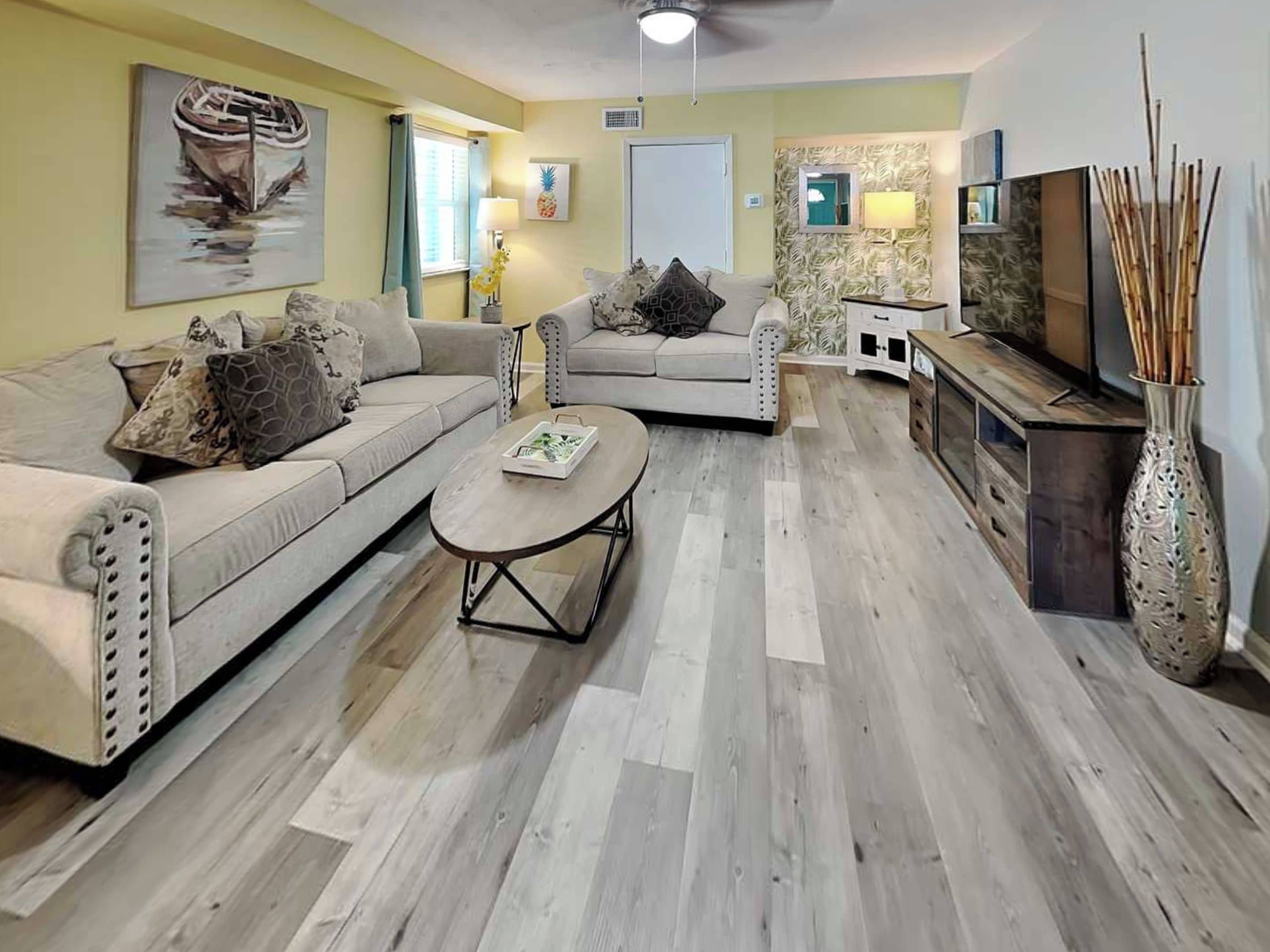 A living room with two sofas, a coffee table, a TV, and a decorative vase.