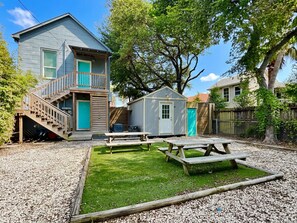 A two-story house with a front porch, a small shed, and a picnic table area.