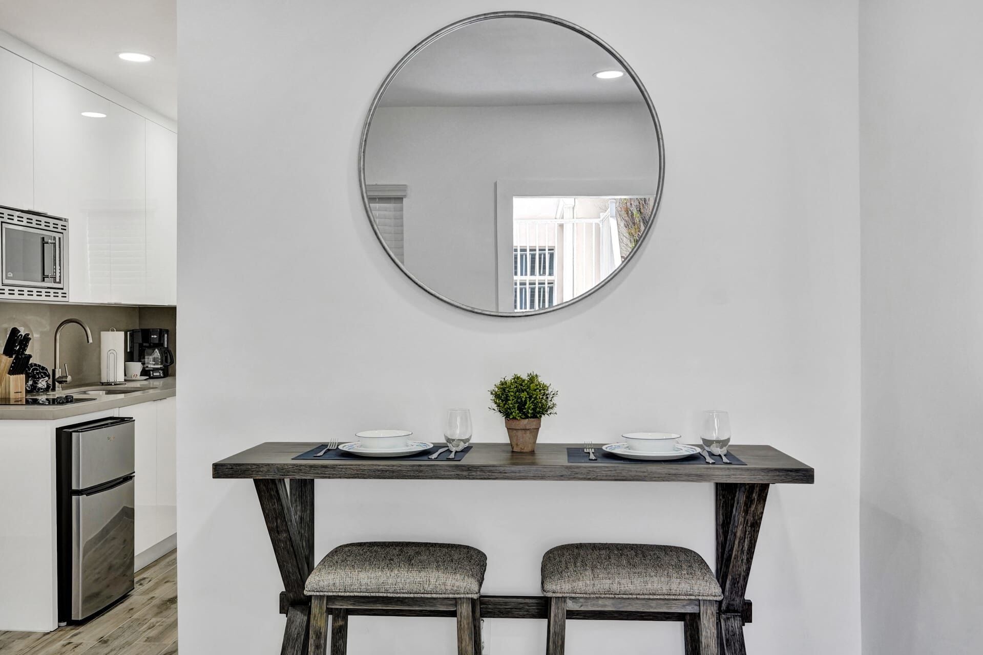 A modern kitchen with white cabinetry, a stainless steel refrigerator, and a coffee maker.
