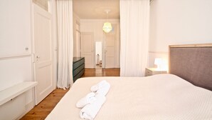 A hotel room with a large bed, a dresser, a mirror, and a nightstand with a lamp. - Bluebell Duplex Apartment, Anjos, Lisbon (Lisboa)