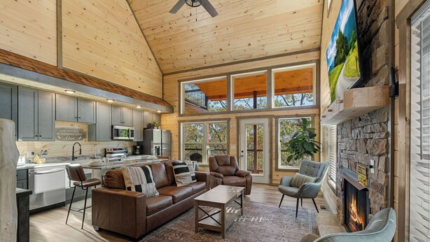 A spacious living area with a fireplace, comfortable seating, and large windows offering views of the outdoors.