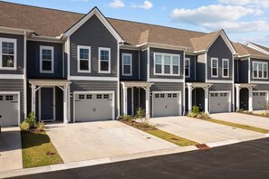 A row of townhouses with attached garages, a driveway, and a well-maintained lawn.