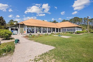 A two-story building with a covered patio area and a paved walkway leading to the entrance. - Birdie Bungalow- Games, Beach Gear, Sleeps 10 (North Myrtle Beach)