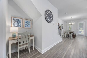 A hallway with a dining area, a staircase, and a clock on the wall.