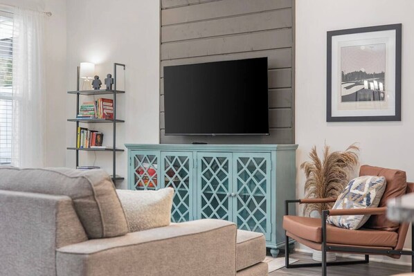 A living room with a sofa, a chair, a television, a bookshelf, and a cabinet.
