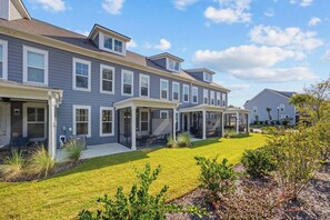 A residential building with a covered patio area and a well-maintained lawn.
