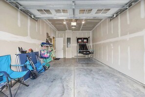 A garage with a basketball hoop, a door, and various items like bags and a stroller.