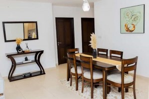 Enjoy meals in this inviting dining area with a wooden table and chairs, a console table, and a beautiful abstract painting.