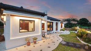 Een modern huis met een goed verlichte gevel, een pad van stenen en een tuin.