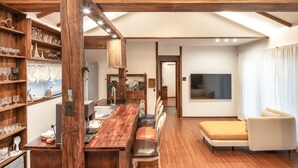 Een ruime woonkamer met een houten eettafel, een bank en een televisie.