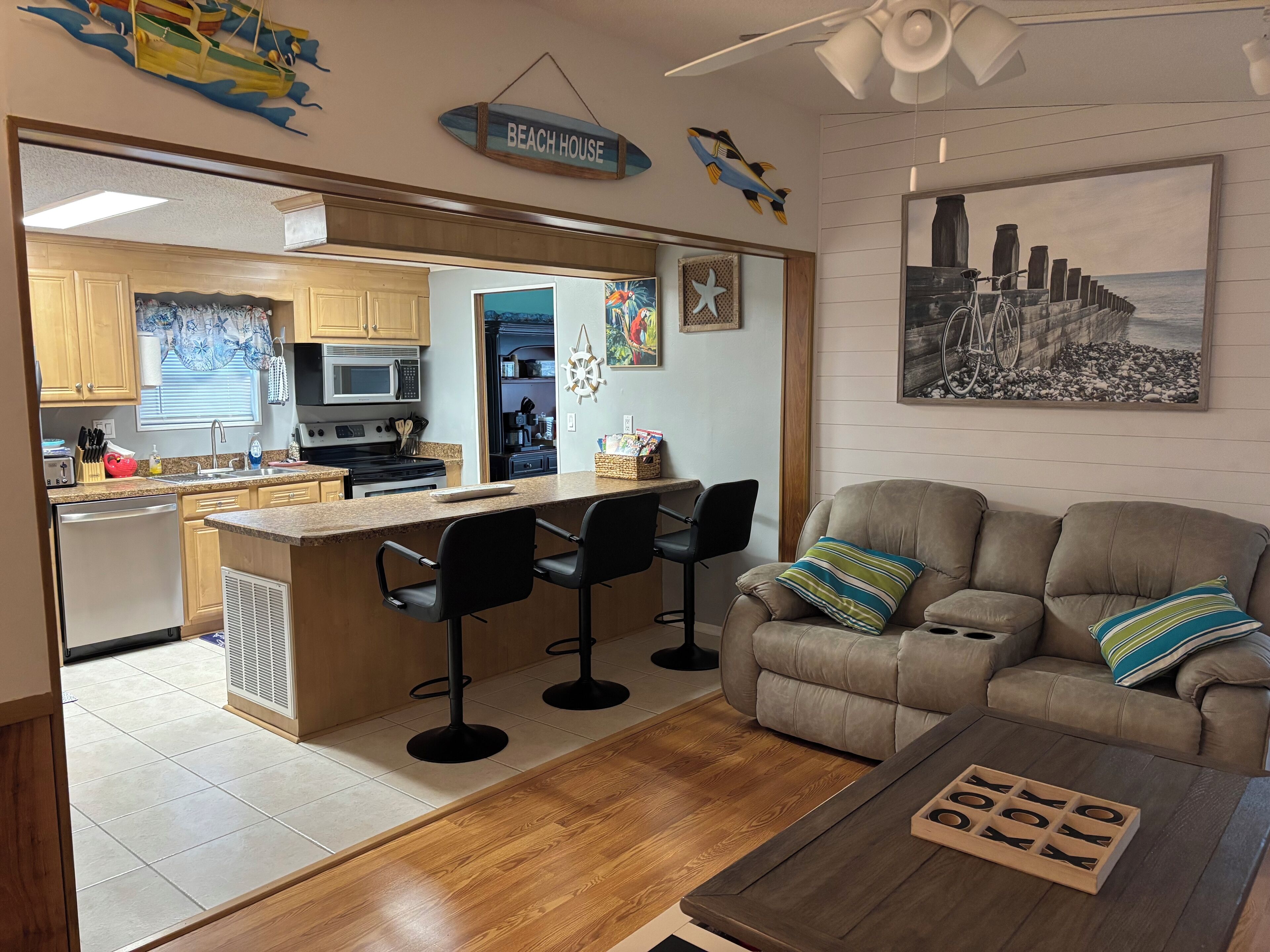 A modern kitchen with a central island, bar stools, and a dining area with a sofa and coffee table.
