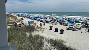 Ein Strand mit vielen bunten Sonnenschirmen und Liegestühlen.