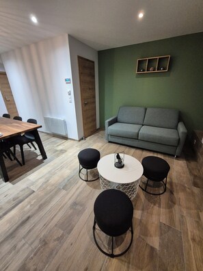 A modern living room with a wooden dining table, a grey sofa, and two black ottomans. - Apartment Tignes (Tignes)
