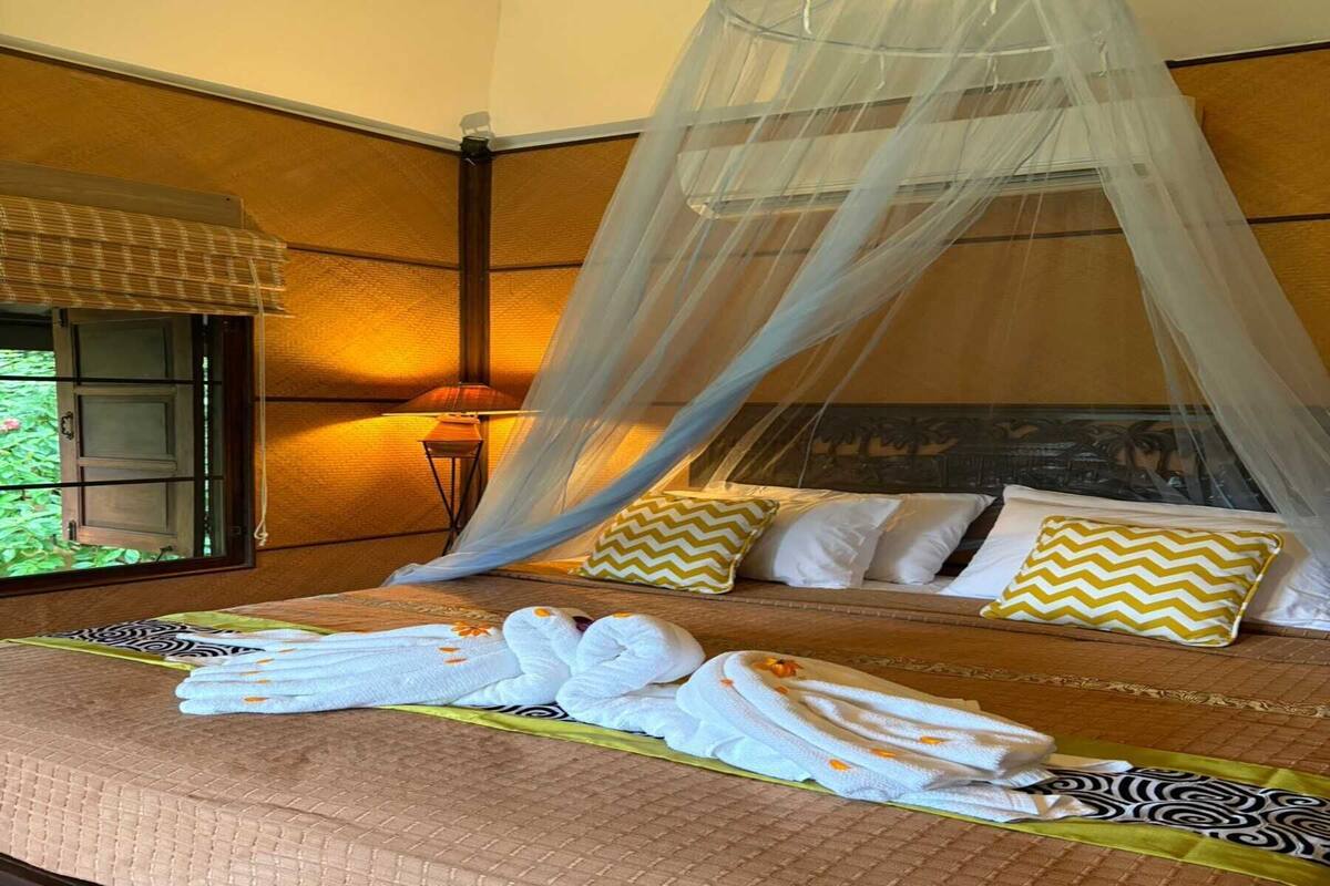 A bed with a canopy, pillows, and towels.