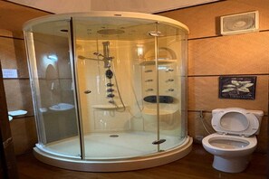 A bathroom with a glass-enclosed shower, a toilet, and a wall-mounted vent.