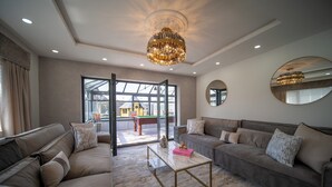 A spacious living room with a large sofa set, a coffee table, and a chandelier. - 22-guest luxury stay with Pool & Bar (Lytham St Annes)