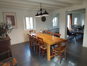 Enjoy meals in this dining area with a long table and six chairs, featuring a pendant light fixture and a dartboard.
