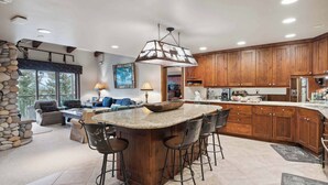 A spacious kitchen with a large island, wooden cabinets, and a stone accent wall.