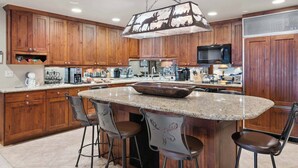 A spacious kitchen with wooden cabinets, a large island with bar stools, and modern appliances.