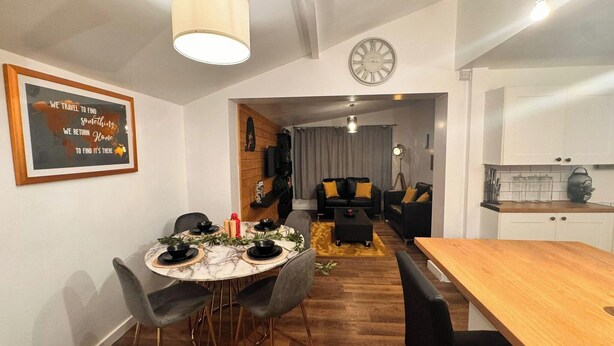 A dining area with a round table, chairs, and a clock on the wall. - Spacious Sheffield Lodge (Sheffield)