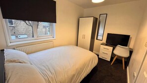 A bedroom with a bed, a desk, a chair, a wardrobe, and a television. - Spacious Sheffield Lodge (Sheffield)