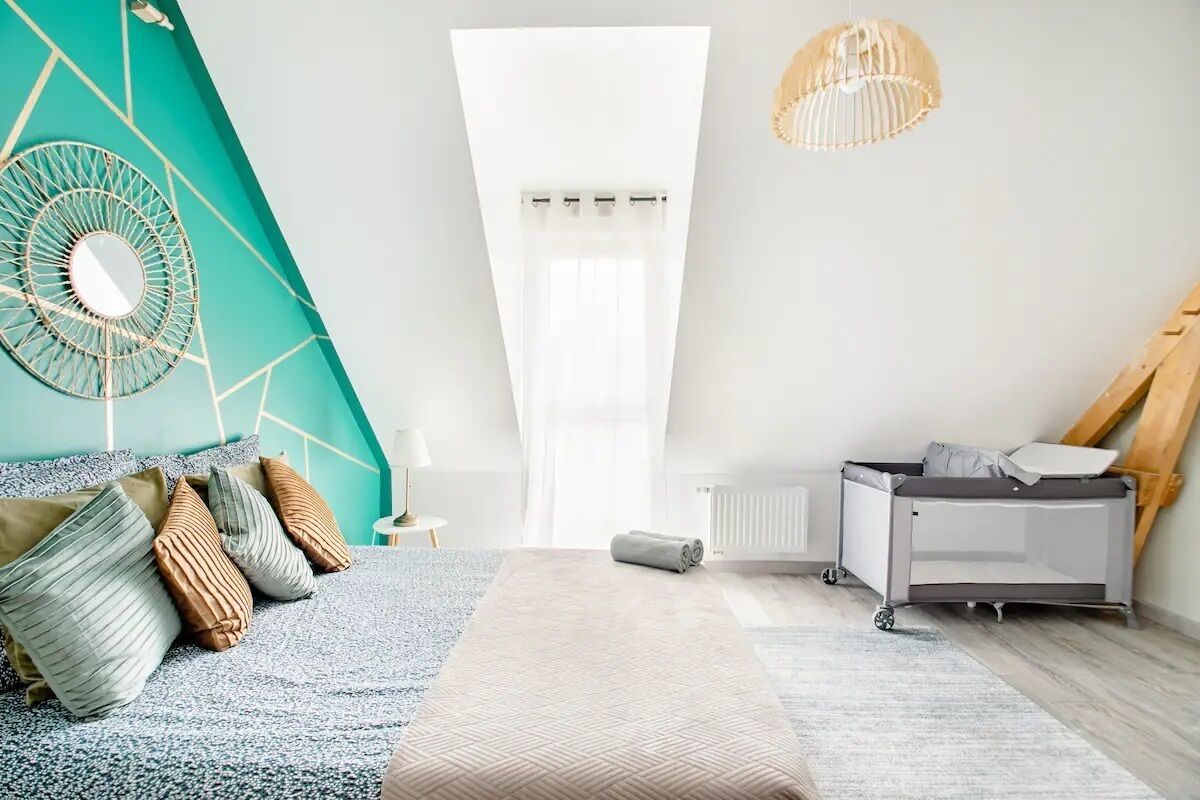 A modern bedroom with a bed, a radiator, a ceiling fan, and a window.