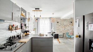 A modern kitchen with a central island, stainless steel appliances, and pendant lighting. - Casa Mogador 10 min from Saint Malo! ideal for families  (Miniac-Morvan)