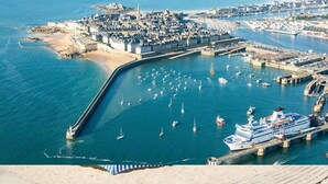 An aerial view of a coastal town with a fortified area, a marina with several boats, and a large cruise ship docked. - Casa Mogador 10 min from Saint Malo! ideal for families  (Miniac-Morvan)