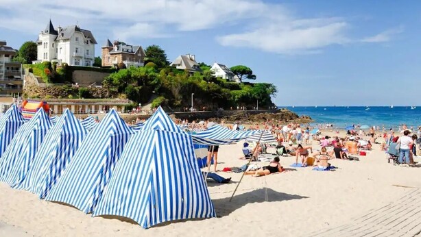 A beach with striped beach umbrellas and a castle in the background. - Casa Mogador 10 min from Saint Malo! ideal for families  (Miniac-Morvan)