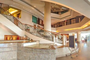 Un interior de varios niveles con una escalera central, una zona de recepción y un amplio atrio.
