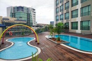 Une piscine sur le toit, dotée d’une structure arquée originale, entourée de plantes en pot et agrémentée d’une terrasse en bois.