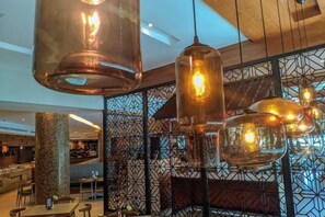 A modern interior with hanging pendant lights, a patterned wall, and a seating area.