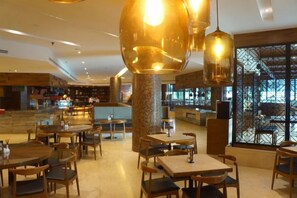 A restaurant with round tables and chairs, hanging pendant lights, and a view through a patterned window. - Sabah Oriental Hotel Kota Kinabalu (Kota Kinabalu)