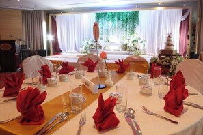 Een feesttafel gedekt voor een formeel evenement, met een podium op de achtergrond.