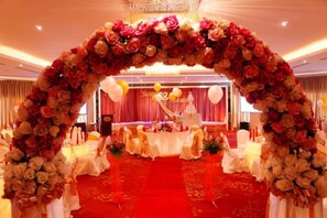A wedding reception setup with a floral arch, tables, and a stage. - Sabah Oriental Hotel Kota Kinabalu (Kota Kinabalu)