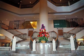 A grand staircase with a floral centerpiece, surrounded by railings and columns, leading to an upper level. - Sabah Oriental Hotel Kota Kinabalu (Kota Kinabalu)