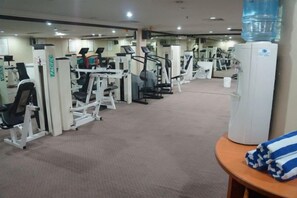 A gym with various exercise machines, a water dispenser, and a towel on a table.
