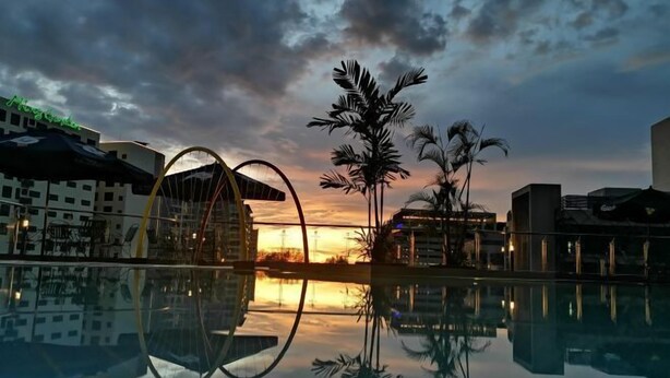 A hotel pool reflecting palm trees and a sunset, with modern architecture and a clear sky. - Sabah Oriental Hotel Kota Kinabalu (Kota Kinabalu)