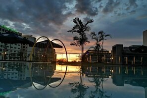 A hotel pool reflecting palm trees and a sunset, with modern architecture and a clear sky. - Sabah Oriental Hotel Kota Kinabalu (Kota Kinabalu)