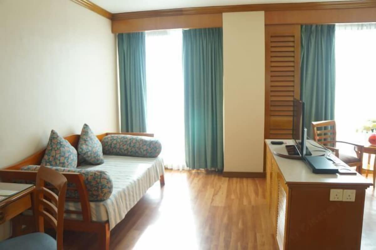 A room with a bed, a desk, a chair, and a window with curtains.