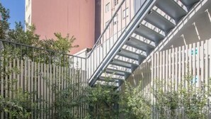 A courtyard with a table and chairs, surrounded by a wooden fence and potted plants. - ALMADA 151 (Porto)